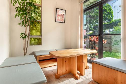 a table and benches in a room with a window at IsShoNi house in Tainan