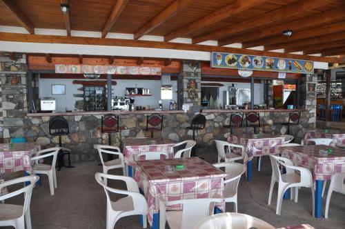 a restaurant with tables and chairs and a stone wall at Paralia guest house in Agia Roumeli