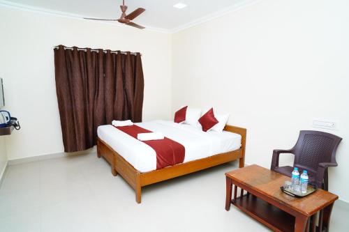 a bedroom with a bed and a table and a chair at Harish Beach Resort in Rāmeswaram