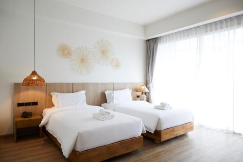 two beds in a hotel room with white sheets at The Leela Resort & Spa Pattaya in Pattaya