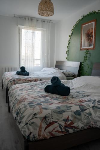 - 2 lits avec des serviettes assises dans une chambre dans l'établissement Chaleureux T3 aux pieds du Stade de France, à Saint-Denis