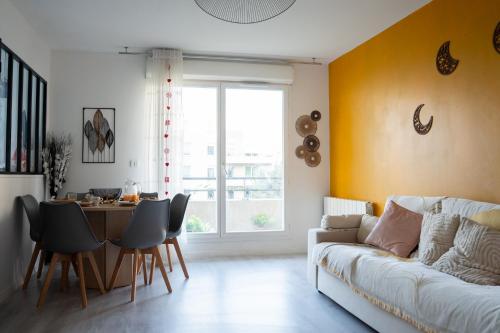 ein Wohnzimmer mit einer weißen Couch und einem Tisch in der Unterkunft Chaleureux T3 aux pieds du Stade de France in Saint-Denis