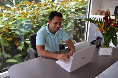 a man sitting at a table using a laptop computer at Moulin Kann Villas in Mahe
