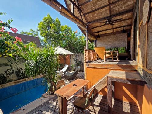 a patio with a table and chairs and a pool at Apalagi Villas in Gili Air