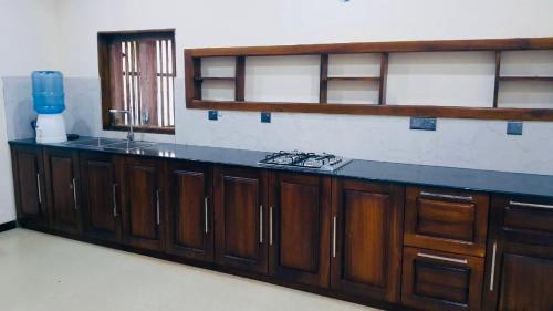a kitchen with wooden cabinets and a counter top at Peace Villa - Homestay in Dickwella