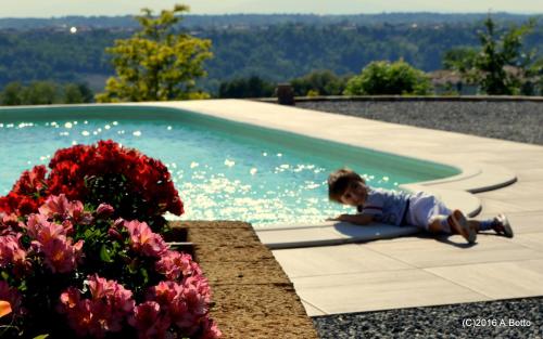 a little boy sitting next to a swimming pool at Rosso Di Sera in Novello