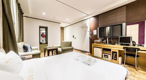 a hotel room with a bed and a flat screen tv at Nostalgia Hotel in Paju