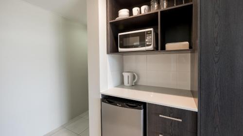 a small kitchen with a microwave and a refrigerator at Alivio Hotel Cairns in Cairns
