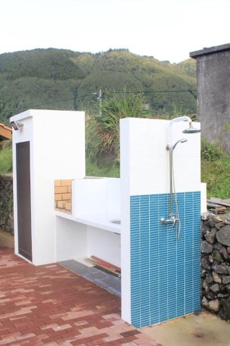 a shower with blue tile on the side of a building at Casa dos Manos in Furnas
