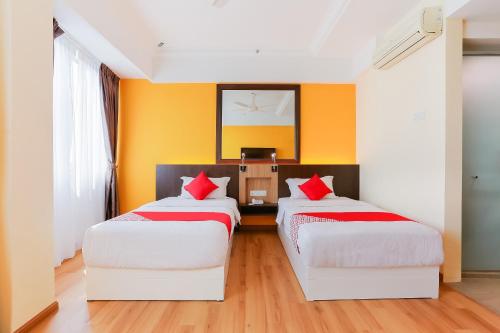two beds in a room with orange walls at Dancenter Super Cowboy Hotel Melaka in Melaka