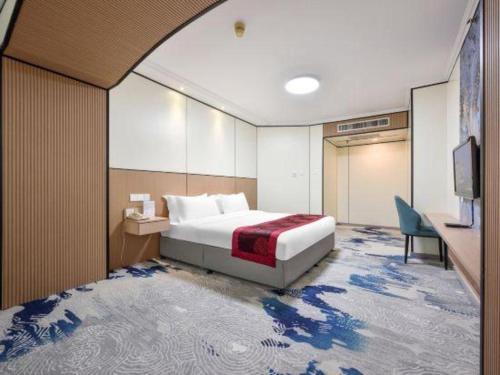 a bedroom with a bed and a desk and a tv at Dalian Bohai Pearl Hotel in Dalian
