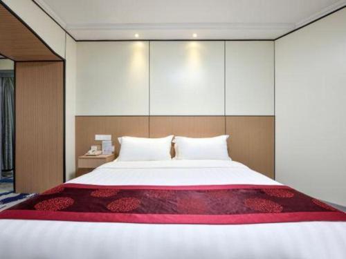 a bedroom with a large white bed with a red blanket at Dalian Bohai Pearl Hotel in Dalian