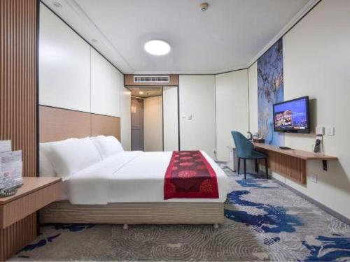 a hotel room with a large bed and a desk at Dalian Bohai Pearl Hotel in Dalian