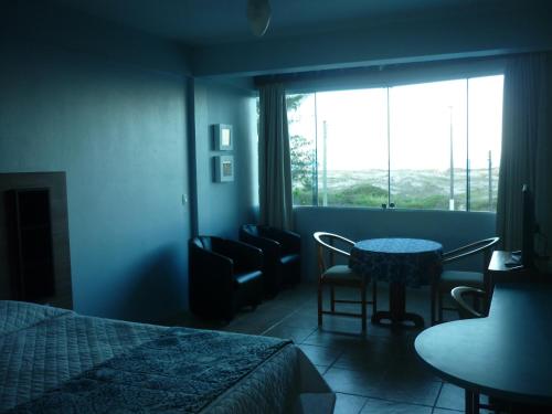 a bedroom with a bed and a table and a window at De Rose Praia Hotel in Torres