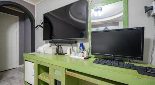 a computer monitor and keyboard on a green desk at Luxury Motel Daejeon in Daejeon