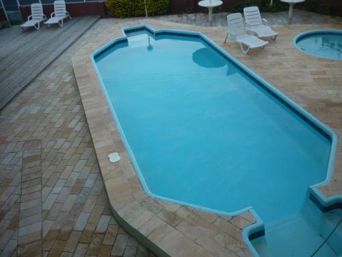 an empty swimming pool in a patio with chairs at De Rose Praia Hotel in Torres