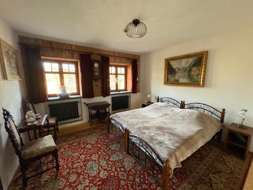a bedroom with a bed and a chair and windows at Feltlův mlýn v Borovnici in Borovnice