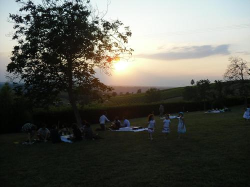 a group of people sitting in a field at sunset at Rosso Di Sera in Novello