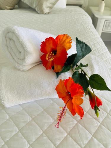 a pile of towels and flowers on a bed at Lovely Seafront Apartment with Breathtaking Seaviews in Cupecoy