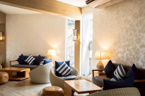 a living room with couches and chairs and a window at The Leela Resort & Spa Pattaya in Pattaya