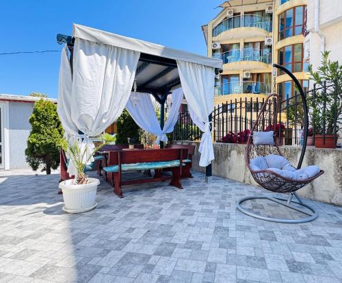 a patio with a canopy and a bench and a table at Villa SUN in Kiten