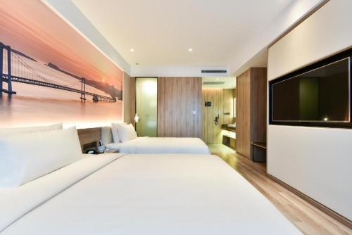 a bedroom with two beds and a flat screen tv at Atour Hotel Dalian Lvshunkou in Dalian