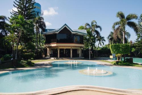 a large pool with a fountain in front of a building at La Traviesa Hotel Resort in General Trias