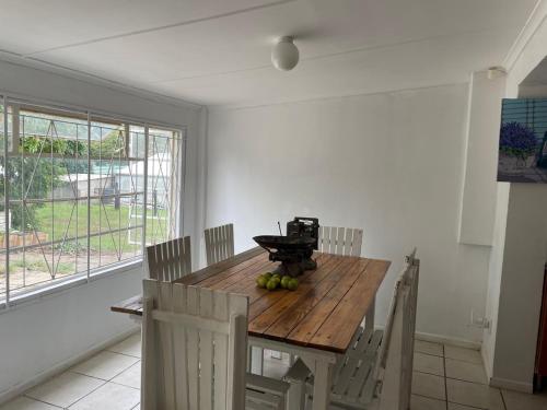 a dining room table with chairs and a wooden table with fruit on it at Evergreen Avocado Orchard in Alexandria