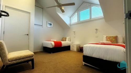 a attic room with two beds and a chair at Pelican Escape Executive Home in Cams Wharf