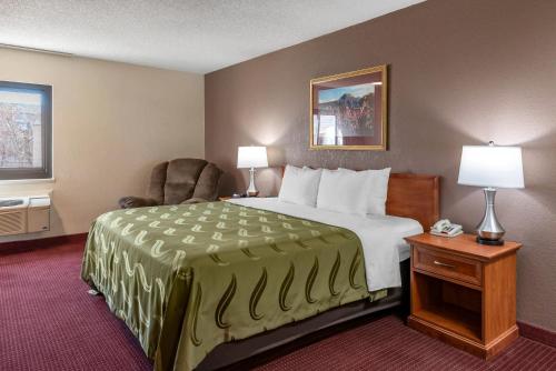 a hotel room with a large bed and a chair at Quality Inn Grand Junction near University in Grand Junction