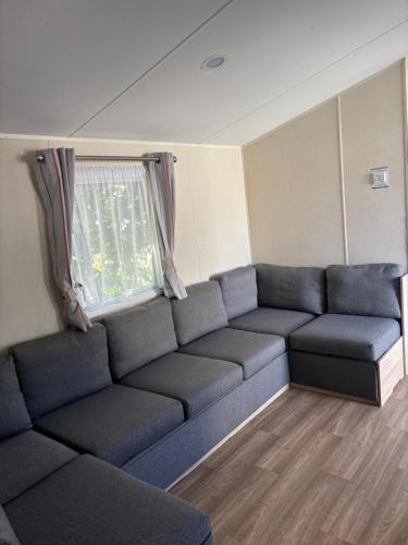 a living room with a couch and a window at Singh&Leite Family caravan for 10 people with 2toilets and lovely Decking in Jaywick Sands
