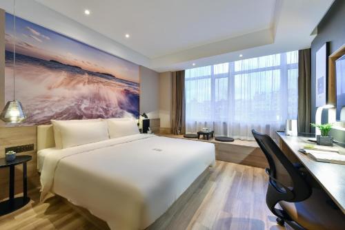 a bedroom with a large white bed and a desk at Atour Hotel Dalian Lvshunkou in Dalian
