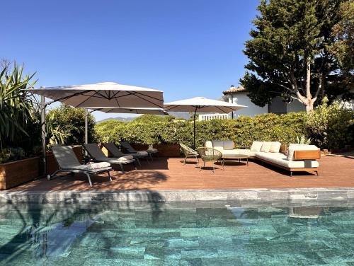 - une piscine avec des chaises longues et des parasols à côté dans l'établissement VILLA Bella CANNES Croix des Gardes, à Cannes