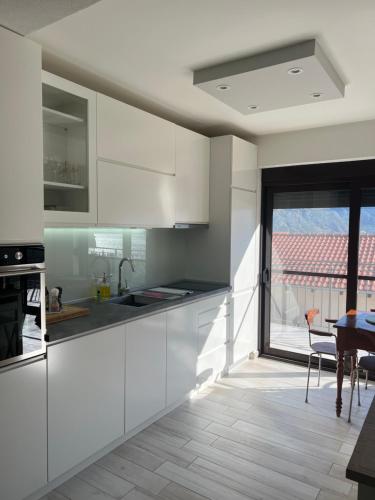 a kitchen with white cabinets and a large window at Salice in Prčanj