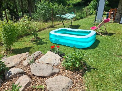 a blue boat in a yard with a chair and flowers at Chata Alaska in Jáchymov