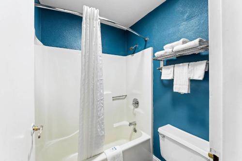 a bathroom with a white shower curtain and blue walls at Rodeway Inn in West Memphis