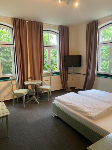 a bedroom with a bed and a table and windows at Alte Wassermühle in Lenzen