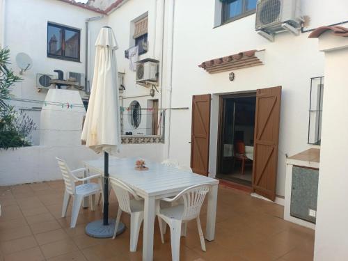 a white table and chairs and an umbrella on a patio at Casa a 5 minutos playa Riells in L'Escala