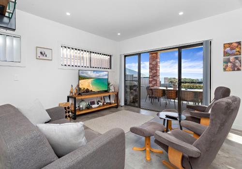 a living room with a couch and chairs and a tv at Fadden Street Retreat in Kiama