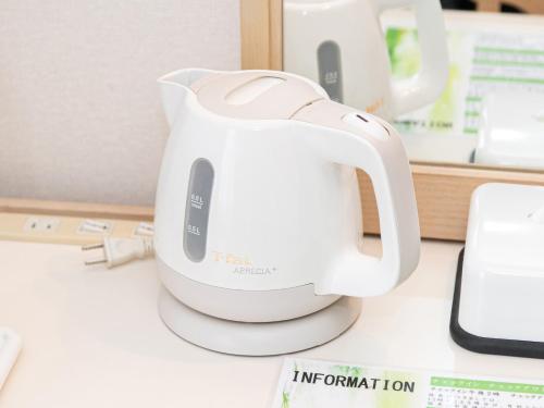 a white tea kettle sitting on a desk at Hotel Verfort Hyuga in Hyuga