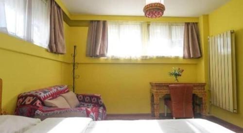 a bedroom with two beds and a couch and window at Tashitakge Hotel in Lhasa