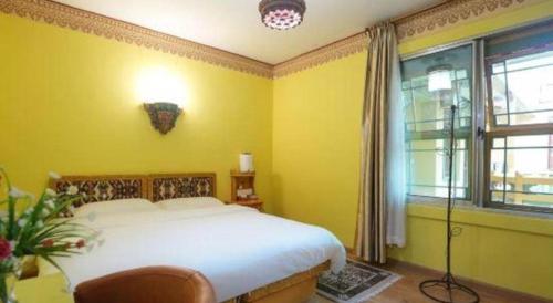a bedroom with a white bed and a yellow wall at Tashitakge Hotel in Lhasa