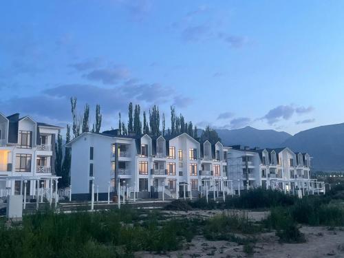 a row of houses with trees and mountains in the background at Shaika resort Bibllan apartmens in Chon-Sary-Oy