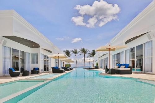 a pool at a resort with chairs and umbrellas at The Privilege Hotel Ezra Beach Club in Bang Rak Beach
