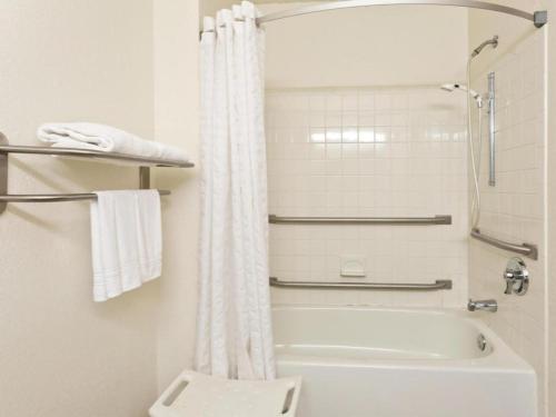 a bathroom with a white shower curtain and a toilet at Super 8 By Wyndham Lexington Park/California Area in California