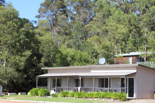 a white house with a balcony and trees at Walpole Rest Point Caravan Park in Walpole