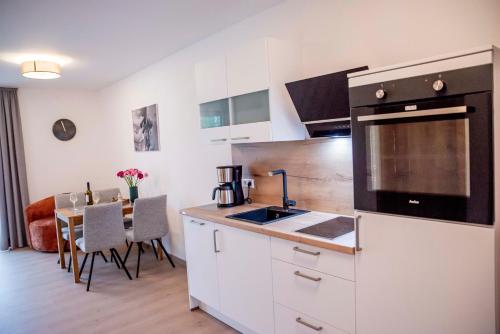 a kitchen with white cabinets and a dining room with a table at Weingut Erich Serwazi in Mesenich