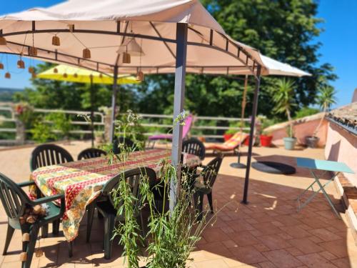a table and chairs under an umbrella on a patio at Le Jardin Secret in Monflanquin