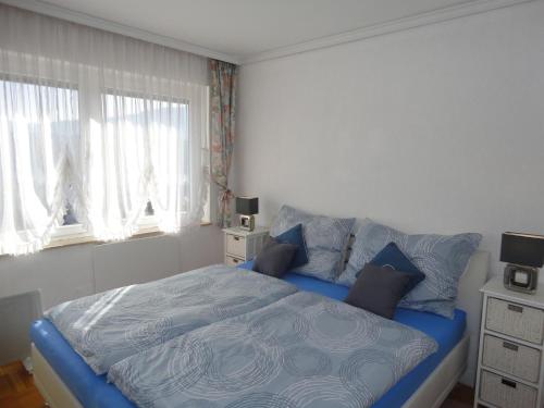 a bedroom with a blue bed and two windows at Ferienwohnung Seeblick Aigner in Seeboden