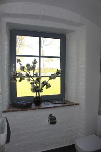 a window in a bathroom with a vase with flowers at Vārves Muiža in Vārve